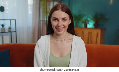 Close-up Portrait Of Happy Smiling Caucasian Girl In Shirt, Looking At Camera, Celebrate Good News. Young Woman Indoor Isolated At Home In Living Room Sitting On Orange Couch. Female Nature Beauty