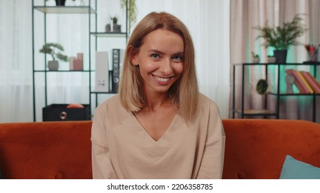 Close-up Portrait Of Happy Smiling Caucasian Girl In Shirt, Looking At Camera, Celebrate Good News. Young Woman Indoor Isolated At Home In Living Room Sitting On Orange Couch. Female Nature Beauty