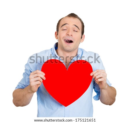 Closeup portrait of happy smiling handsome funny looking man, holding large red heart to chest daydreaming of women in love, isolated on white background. Positive emotions, facial expression feelings