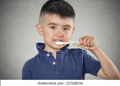 Closeup portrait happy, smiling little boy brushing his teeth with toothpaste, manual toothbrush isolated grey wall background. Oral dental health, disease prevention. Positive face expressions - Powered by Shutterstock