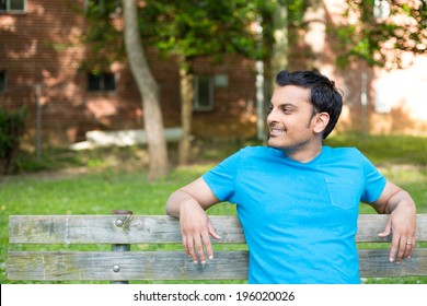 Closeup Portrait, Happy Smiling, Regular Young Man In Blue Shirt Sitting On Wooden Bench, Relaxed Looking To Side, Isolate Background Trees, Woods