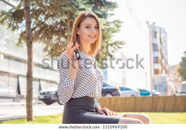 Closeup\
portrait happy, smiling, young attractive woman, buyer near her new\
car showing key isolated outside dealer, dealership lot office.\
Personal transportation, auto purchase\
concept