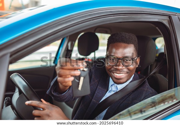 Closeup portrait
happy, smiling, young man, buyer sitting in his new blue car
showing keys isolated outside dealer, dealership lot. Personal
transportation, auto purchase
concept