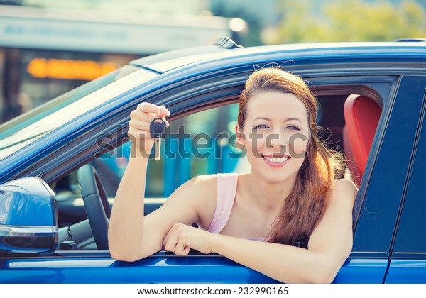 Closeup portrait happy, smiling, young attractive\
woman, buyer sitting in her new blue car showing keys isolated\
outside dealer, dealership lot office. Personal transportation,\
auto purchase concept