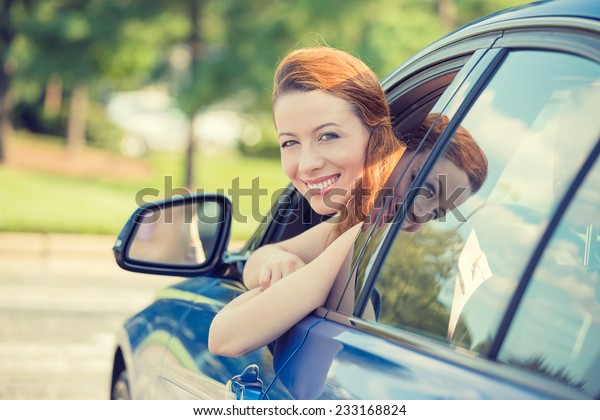 Closeup portrait happy smiling young attractive\
woman buyer sitting in her new car excited ready for trip isolated\
outside dealer dealership lot office. Personal transportation auto\
purchase concept