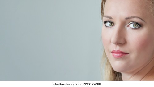 Close-up portrait of happy young beautiful woman face looking at camera. Blonde woman with green eyes. Copy space. 
