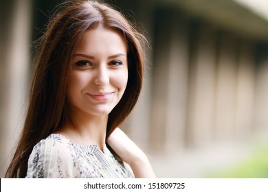Closeup portrait of a happy young brunette teenage girl outdoor. Copyspace