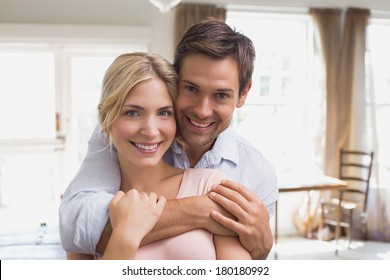 Close-up portrait of a happy young man embracing woman from behind at home - Shutterstock ID 180180992