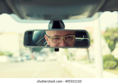 Closeup Portrait, Happy Young Man Driver Looking At Rear View Mirror Smiling, Isolated Interior Car Windshield Background. Positive Human Expression Body Language