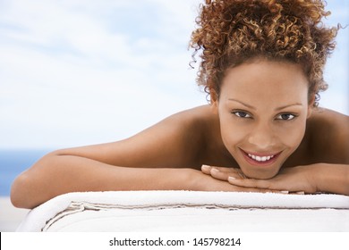 Closeup portrait of happy young woman lying on massage table outdoors