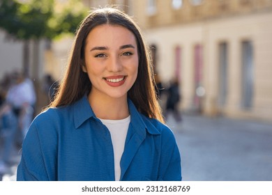 Close-up portrait of happy young woman face smiling friendly, glad expression looking at camera dreaming, resting, relaxation feel satisfied good news outdoors. Pretty girl in urban city sunny street - Powered by Shutterstock