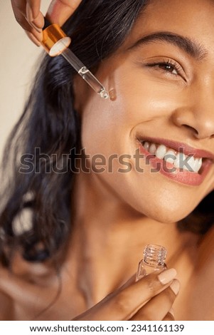 Closeup portrait of happy young woman applying anti aging serum on face. Beautiful latin woman moisturizes her skin. Detail of healthy and skin care conscious multiethnic girl using facial serum.
