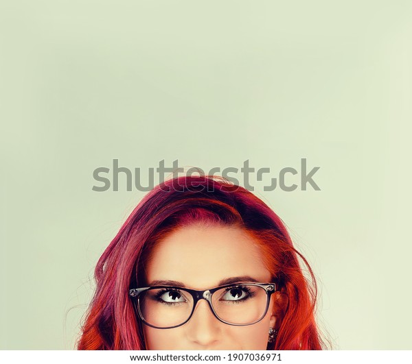  Closeup portrait headshot thoughtful cute woman\
face above nose looking up isolated on green wall background with\
copy space above head. Human face expressions, emotions, feelings\
body language