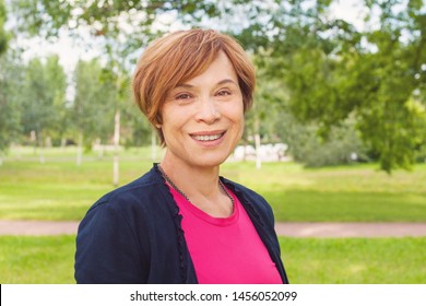 Closeup Portrait Of Healthy Smiling Older Woman Outdoors. Elegant Mature Redhead Woman With Short Hair Smiling