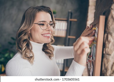 Close-up portrait of her she nice attractive lovely cute smart clever cheerful wavy-haired girl hr recruiter pinning notes on board in modern loft brick industrial interior style workplace station