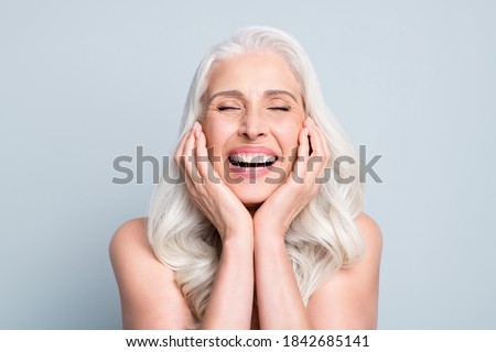 Close-up portrait of her she nice attractive excited cheerful grey-haired elderly lady touching cheeks laughing isolated gray pastel color background