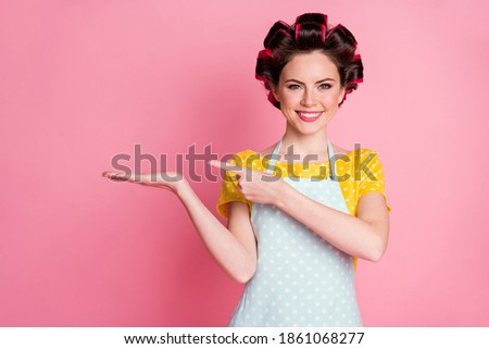 Close-up portrait of her she nice lovely cheerful housewife holding on palm demonstrating copy space isolated over pink pastel color background