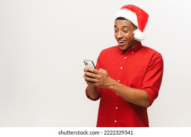 Close-up portrait of hilarious man in santa hat using smartphone isolated on white, young guy sending New Year congratulations, texting online - Powered by Shutterstock