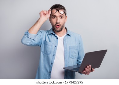 Close-up portrait of his he nice attractive wondered shocked stunned successful gray-haired guy it geek using laptop isolated over gray light pastel color background