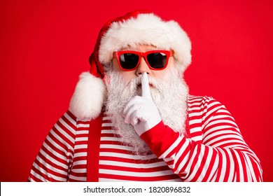 Close-up portrait of his he nice handsome mysterious white-haired Santa wearing sunglasses showing shh sign silence silent mute isolated over bright vivid shine vibrant red color background - Powered by Shutterstock