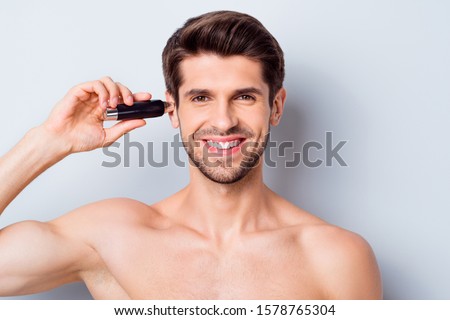 Close-up portrait of his he nice attractive bearded cheery brown-haired guy shaving picking cutting unwanted hair in ear using modern cutter device isolated on light white grey color pastel background
