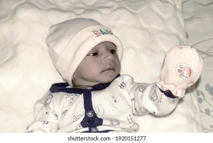 Closeup Portrait Image Of Cute Beautiful Adorable Baby Boy Asian And Indian Ethnicity In Winter Clothing Lying Of Bed On White Blanket. One Month Old Sweet Toddler Posing On Playing Mood. Front View.