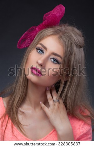 Close-up portrait, isolated, Blonde model looks like Barbie with pink lips and blue eyes with pink bow 