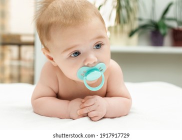 Retrato de cerca de un niño pequeño con un pacificador en la boca. Encantador bebé de 3 meses de edad de ojos grises.