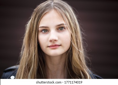 close-up portrait of little beautiful stylish kid girl with long flowing hair against a brown striped wall