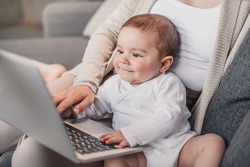 Closeup Portrait Of Little Boy With Funny Facial Expression Sitting On Mother's Knees And Exploring Laptop 