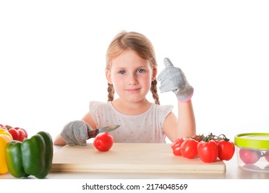 A Closeup Portrait Of A Little Girl Cutting Vegetables On A Wooden Board Wearing Safety Gloves