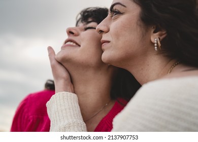 Closeup Portrait Of Lovely Young Girlfriends Faces Hugging Looking Outside In A Cloudy Day - Shallow Depth Of Field Main Focus On The Right Woman Eye