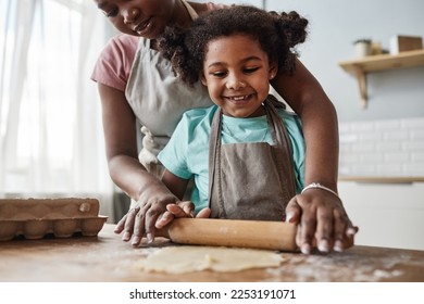 Closeup portrait of loving mother and daughter baking together at home and rolling dough, copy space - Powered by Shutterstock