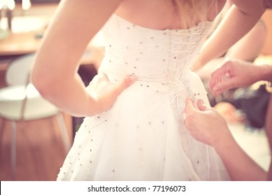 Closeup Portrait Of A Maid Of Honor Helping The Bride With Her Dress