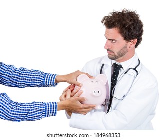 Closeup Portrait, Male Healthcare Professional, Doctor, Nurse With Stethoscope Protecting Piggy Bank,while Someone Hands Trying To Steal It, Isolated White Background. 