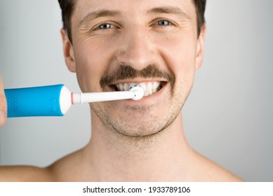 Close-up portrait of a man with a modern electric toothbrush. Man brushing teeth, daily hygiene procedure. Oral health
