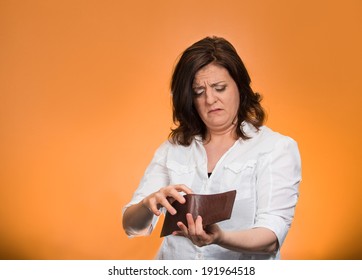 Closeup Portrait, Mature, Sad, Middle Aged, Surprised, Unhappy, Puzzled Woman, Shocked, Holding, Showing Empty Wallet, Isolated Orange Background. Negative Human Emotions, Facial Expressions, Reaction