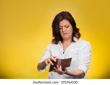 Closeup Portrait, Mature, Sad, Middle Aged, Surprised, Unhappy, Puzzled Woman, Shocked, Holding, Showing Empty Wallet, Isolated Yellow Background. Negative Human Emotions, Facial Expressions, Reaction