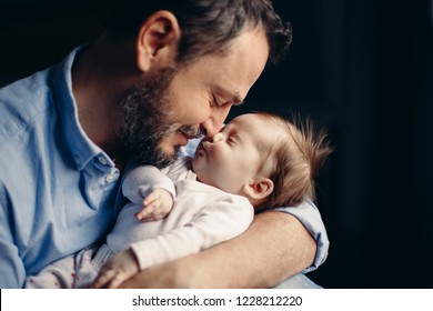 Closeup Portrait Of Middle Age Bearded Caucasian Father Hugging And Kissing Newborn Baby. Man Parent Holding Child. Authentic Lifestyle Real Life Touching Tender Moment. Single Dad Family Life