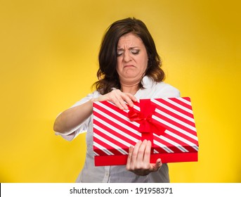 Closeup Portrait Middle Aged Woman Holding, Opening Gift Box, Displeased, Disgusted, What She Received, Isolated Yellow Background. Negative Human Emotion, Facial Expression, Feeling Attitude Reaction