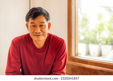 Close-up portrait of a middle-aged Asian male model with short black hair wearing a red t-shirt. smiling in a coffee shop - Powered by Shutterstock