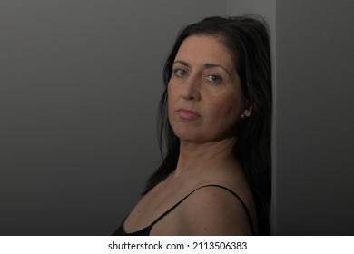 Close-up Portrait Of Middle-aged Spanish Woman With Black Hair, Light Eyes And Gray Background