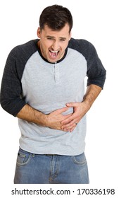 Closeup Portrait Of Miserable, Upset, Young Man, Doubling Over In Stomach Pain, Looking Very Sick, Isolated On White Background. Facial Expressions Emotion Feelings, Health Issues