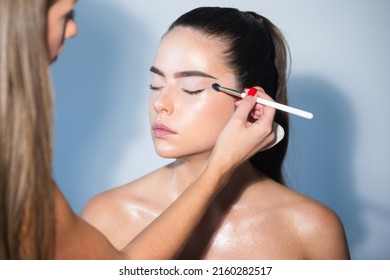 Closeup Portrait Of A Model With Bright Makeup On A Face. Makeup Artist Applies Eye Shadow. Hand Of Visagiste, Painting Cosmetics Of Young Beauty Model Girl.