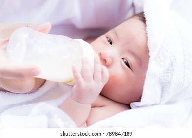 Closeup portrait of mother feeding newborn baby by milk bottle