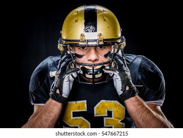 Close-up portrait of muscular american football player in uniform adjusting helmet isolated on black - Powered by Shutterstock