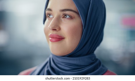 Close-up Portrait Of Muslim Businesswoman Wearing Hijab Looks Thoughtfully Afar And Smiles. Beautiful Woman Wearing Traditional Headscarf. Successful Empowered Arab Woman.