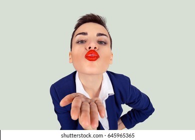 Closeup portrait of nerdy young funny distorted woman face with big red lips blowing sending  a kiss to you camera, isolated light green white background - Shutterstock ID 645965365