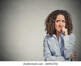 Closeup portrait nervous looking woman biting her fingernails craving something anxious isolated grey wall background with copy space. Negative human emotion facial expression body language perception