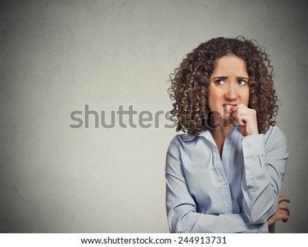 Closeup portrait nervous looking woman biting her fingernails craving something anxious isolated grey wall background with copy space. Negative human emotion facial expression body language perception